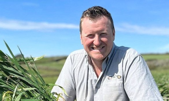 A man (Pete Olds) crouching in a field holding crops.